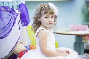 bielorrusia, el ciudad de gomil, diciembre 27, 2018. Mañana fiesta en kindergarten.hermosa niña en un blanco vestir sesión. Tres año antiguo niña en día festivo. foto