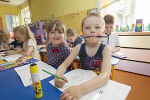 niños en un dibujo lección en jardín de infancia. gracioso preescolar con lápiz y cuaderno foto