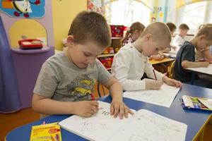 Belarus, the city of Gomel, April 25, 2019. Open day in kindergarten.Children draw. Preschoolers are engaged in a lesson.Boy with a pencil and an album. photo