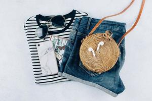 Flat lay with summer women's clothing and accessories. Striped t-shirt, denim shorts, rattan bag photo