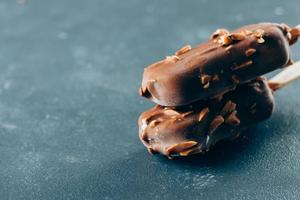 Two portion of Eskimo ice cream in chocolate glaze on blue background. Yummy sweet food snack treat photo