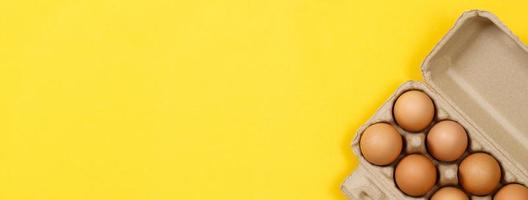 Chicken eggs in a cardboard box ready to cook on a yellow background photo