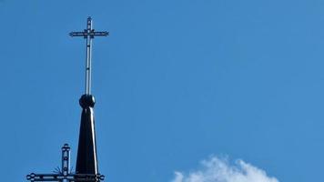 un cruzar en parte superior de un Iglesia en contra un azul cielo con nubes tema de cultura, fe y religión. video