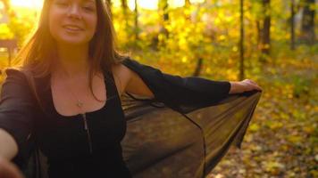 Beautiful girl holds the hand of her boyfriend and follows him through the yellow autumn forest. Slow motion video