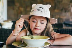 Portrait of adorable happy little girl having lunch or dinner photo