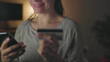 mujer hace en línea pago a hogar con un crédito tarjeta y teléfono inteligente video