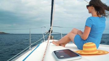 Woman in a yellow hat and blue dress girl rests aboard a yacht near the lighthouse on summer season at ocean video