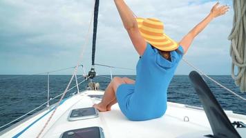 mujer en un amarillo sombrero y azul vestir niña descansa a bordo un yate cerca el faro en verano temporada a Oceano video