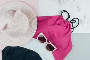 Woman's beach accessories one piece swimsuit, sunglasses and hat on background photo