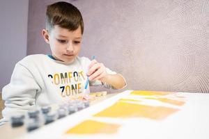 Left handed boy is painting by numbers with gouache at home. Comfort zone. photo