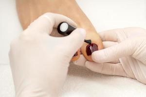 Pedicurist applying burgundy nail polish photo