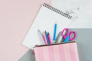 Back to school concept. School supplies in pencil case. Pink background with copy space. Flat lay photo