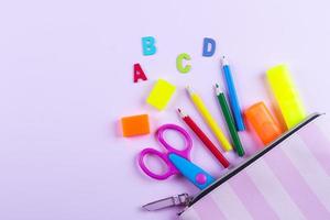 Back to school background. School supplies in pencil case. Pink background with copy space, top view photo