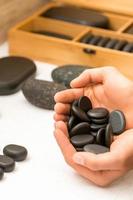 Hands holding spa black pebbles photo