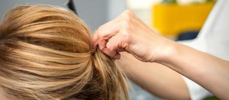 Female hairdresser styling blonde hair photo