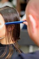 Hairdresser cuts wet hair of woman photo