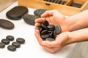 Hands holding spa black pebbles photo