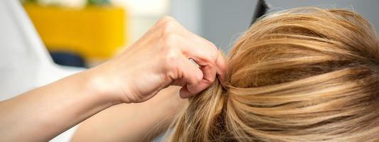 Female hairdresser styling blonde hair photo