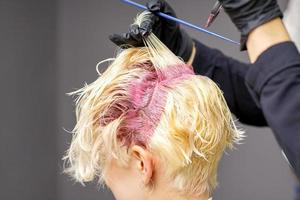 Hairdresser's hands applying pink dye photo