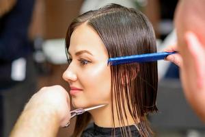 Hairdresser cuts wet hair of woman photo