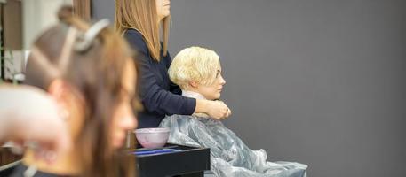 Hairdresser puts on transparent cape photo