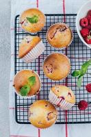 Berry raspberry muffins on metal grill for cooling on light concrete background. Top view. photo