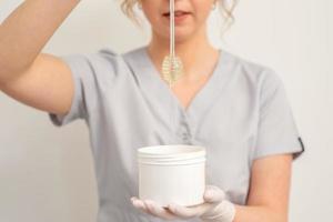 Beautician holding bowl with wax photo