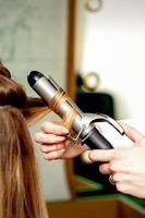 Hairdresser curling hair with curling iron photo