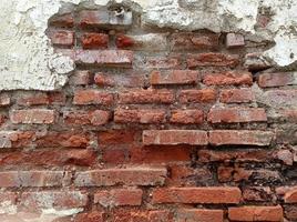 Broken wall revealing the bricks in it. Rustic and vintage wall background. photo