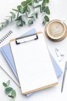 Modern white office desk table with coffee, notebook and other supplies. photo