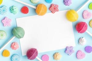 Sweet lollipops and candies and blank greeting card on blue background photo