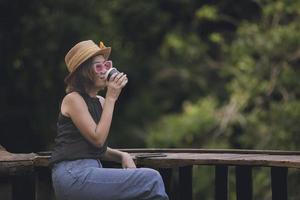 hermosa asiático mujer Bebiendo caliente café en tomar un camino taza foto