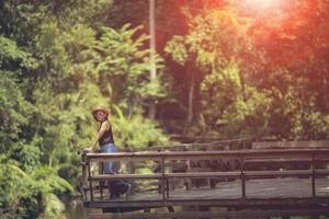 woman standing on wooden patio against deep green forest photo