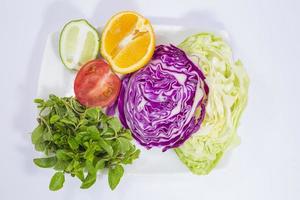 A plate of vegetables and fresh lime and lemon. photo