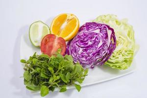 A plate of vegetables and fresh lime and lemon. photo