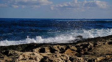 Blue sea wave and white foam and splash. Stone beach on island of Malta, no sandy beach. Summer holiday border frame concept. Tropical island vacation backdrop. Tourist travel banner design template. photo