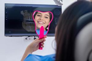 Happy teenager admiring teeth in mirror photo