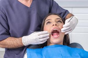 Crop dentist inspecting opened mouth of teenager photo