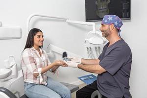 Smiling doctor giving teeth aligners to female patient photo