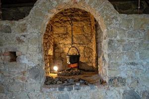 antique kitchen hearth in a historic castle with a metal pot photo