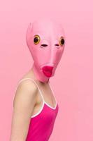 moderno Víspera de Todos los Santos disfraz en un silicona máscara en el forma de un rosado pescado cabeza en un sexy traje. el concepto de un loco Mira foto