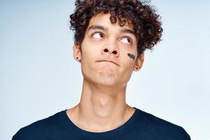 curly-haired guy in a black t-shirt cosmetics on the face clean skin photo