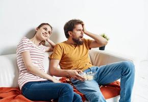 Man with plates popcorn and woman on orange plaid sofa family friends having fun photo