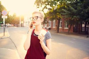 mujer con corto pelo en el calle hablando en el teléfono un taza de bebida foto