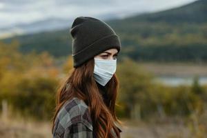 médico mascaras y en calentar gorra son mirando a el lado en naturaleza en el bosque foto