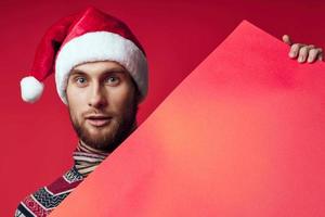 hermoso hombre en un Papa Noel sombrero participación un bandera fiesta rojo antecedentes foto