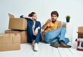 Married couple man and woman on wooden floor with boxes moving flower in a pot repair work photo