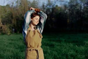 Portrait of a woman with a beautiful smile in her work clothes and apron in nature, enjoying relaxation after work in the sunset sunlight photo