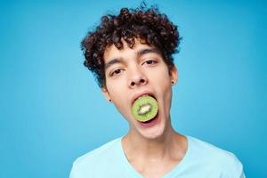 handsome man with kiwi curly hair in his mouth cropped view in blue background photo