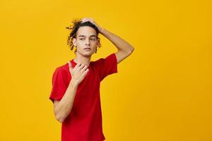 Pensive funny Caucasian young man in red t-shirt point at copy space posing isolated on over yellow studio background. The best offer with free place for advertising. Emotions for everyday concept photo